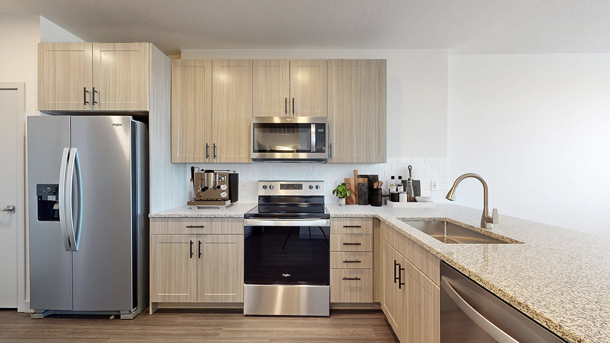 Staged kitchen with stainless steel appliances and custom cabinetry at Railside at Wadsworth